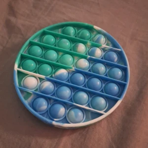 Pop it - En blå grön pop it med tie dye mönster.