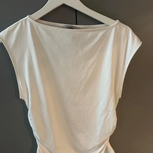 Vitt linne - Vitt linne med lätt drapering i sidan.