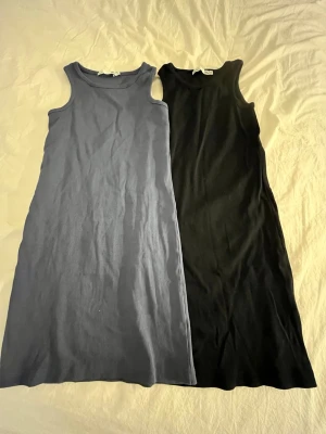 Ribbad svart och blå ärmlös klänning 157 - Två stilrena ribbade klänningar från 157 i svart och marinblått. Båda är ärmlösa med rund hals och rak passform, perfekta för en enkel och clean look. Materialet är mjukt och stretchigt, vilket gör dem riktigt bekväma att bära. Pris kan diskuteras🥰