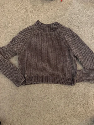 Grå stickad tröja från H&M Divided - Mysig grå stickad tröja från H&M Divided i storlek M. Tröjan har en högre ribbad hals, långärmad modell. 