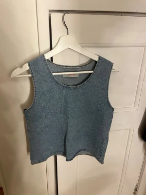 Ärmlös jeanslinnetopp  - Säljer en stilren ärmlös linnetopp i ljusblå denim från VM Jeans. Toppen har rund halsringning och raka sömmar för en clean look. Perfekt att matcha med både kjol och byxor för en cool vibe.