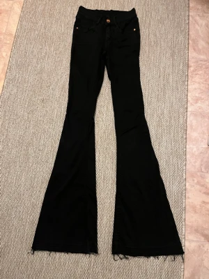 Svarta bootcut jeans med rå kant - Säljer ett par svarta bootcut jeans med rå, fransig kant nertill. Jeansen är hela 84 cm lång.😊