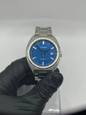 Citizen automatisk - Säljer min Citizen NJ0100-71L med snygg blå urtavla. Klockan är i bra skick och fungerar precis som den ska. 	•	Automatisk urverk (självuppdragande) 	•	Stilren blå urtavla 	•	Boett och länk i rostfritt stål 	•	Håller tiden bra och går fint 	•	Normal bruksslitage kan förekomma, inga större anmärkningar  Klockan levereras med original låda, men utan papper och utan den mjuka innerkudden som klockan normalt sitter på.  En mycket prisvärd automatisk klocka som passar både till vardag och mer uppkläd