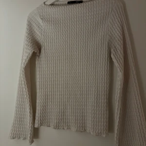 Vit långärmad topp från 157 - Säljer en vit långärmad topp från 157 med vågigt ribbat mönster. Toppen har en figurnära passform och är tillverkad i ett mjukt, stretchigt material som känns skönt mot huden. Perfekt att styla med jeans eller kjol för en clean look. Den är i storlek S. Pris kan diskuteras vid snabb affär