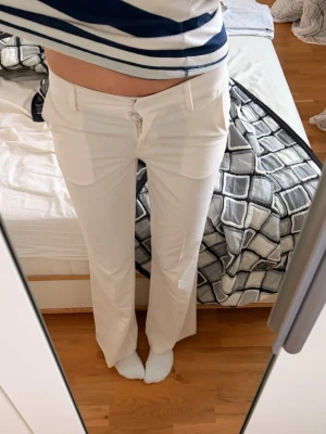 Vita kostymbyxor - Säljer ett par stilrena vita kostymbyxor från Nelly i storlek 32, byxorna har raka ben och låg midija💞💞otroligt snygga för en sommar kvälls outfit🙌☀️innerbenslängd: 81cm     Waist:77cm