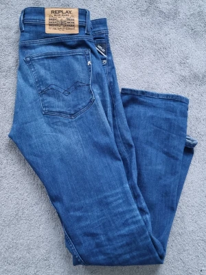 Blå Replay jeansbyxor - Säljer ett par klassiska blå jeans från Replay med snygga detaljer på bakfickan och läderpatch i midjan. Jeansen har normal passform och är tillverkade i mjukt denimtyg som sitter skönt hela dagen. Perfekta till både sneakers och boots. 32L,30W