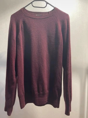 Vinröd kashmirtröja Oscar Jacobson - Mysig vinröd tröja från Oscar Jacobson i mjuk kashmir. Klassisk rund halsringning, långa ärmar och diskret OJ-brodyr nedtill. Perfekt för dig som gillar stilrena och bekväma plagg med exklusiv känsla.