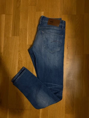 Washed Blå G-Star RAW jeans L3301 - Säljer ett par blå jeans från G-Star RAW, modell L3301. Jeansen har klassisk femficksdesign, normal midja och slim fit. Snygga slitningar och tvättade detaljer ger en avslappnad look. Tillverkade i slitstarkt denim med G-Star-lapp bak i midjan.