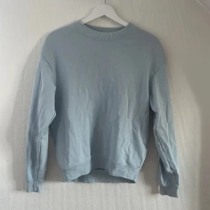 Monki Ljusblå sweatshirt med rund hals - Enkel och stilren ljusblå sweatshirt med rund halsringning och ribbade muddar vid ärmslut och nederkant. Perfekt för en avslappnad look och passar till det mesta. Långärmad och i mjukt material.