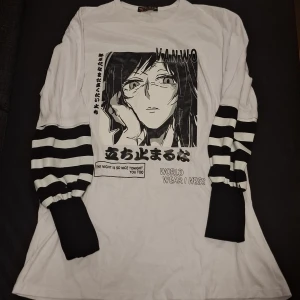 Vit långärmad anime-tröja AVIJEH - Vit långärmad tröja från AVIJEH med svartvitt anime-tryck framtill och text. Ärmarna har breda svarta och vita ränder som ger en cool kontrast. Perfekt för dig som gillar streetstyle och manga vibes.
