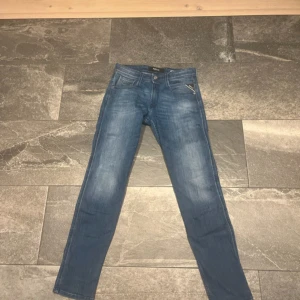 Replay anbass  - Säljer ett par klassiska blå jeans från Replay med snygg tvätt och raka ben. Jeansen har fem fickor, Replay-logga på myntfickan och patch bak i midjan. Perfekt passform och stilren look som funkar till det mesta.