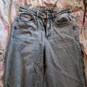 Ljusblå straight jeans från Vero Moda - Säljer ett par klassiska ljusblå jeans från Vero Moda We Do Denim. Jeansen har hög midja, raka ben och fem fickor. De är tillverkade i bomullsdenim och har en snygg vintagekänsla. Perfekta att styla med sneakers eller boots.