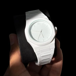 Vit stilren klocka med länkarmband - Snygg vit klocka med minimalistisk design och rund urtavla. Länkarmbandet är i vit plast och baksidan av boetten är i rostfritt stål. Klockan har en klassisk analog visning utan siffror, vilket ger en clean och modern look.