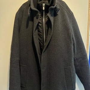 Mörkgrå ullrock från Jack & Jones - Supersnygg mörkgrå rock från Jack & Jones Premium med en Quiltad Innerjacka! Rocken är otroligt varm och klarar utan tvekan Sveriges vinterkyla! Lite smutsig (se sista bilden) men det är ingen vidare defekt då den enkelt kan tvättas! Nypris runt 1500kr och jac tar emot seriösa bud!