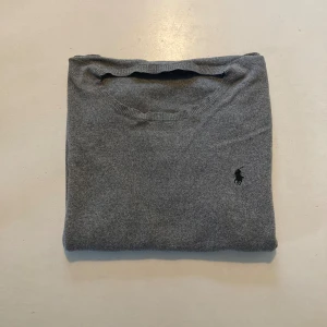 Grå tröja från Polo Ralph Lauren - Säljer en klassisk grå tröja från Polo Ralph Lauren i mjuk pima cotton. Tröjan har rund halsringning, lång ärm och den ikoniska broderade loggan på bröstet. Perfekt basplagg med stilren look. Säljer för halva nypriset!