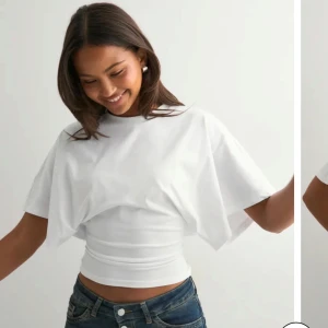 Vit topp med vida ärmar - Säljer en vit topp med breda, korta ärmar och tight passform över midjan. Toppen har rund halsringning och är tillverkad i mjukt bomullstyg. Säljer för den aldrig använts/ för liten. Skriv om du undrar något ❤️