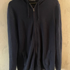 Kashmir zip-hoodie från Charles Tyrwhitt - Mysig mörkblå kashmir zip-hoodie från Charles Tyrwhitt i storlek Large. Tröjan har dragkedja framtill, huva med snören och två fickor. Tillverkad i ett stickat material som passar perfekt för kyligare dagar. Skick 10/10 ☺️