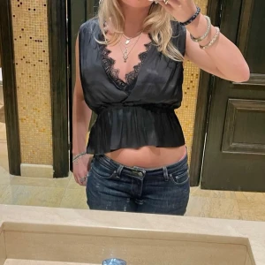 Stockholmstil Svart satin fest topp med spets - En silkeslen kortärmad blus med spets från H&M, använd en gång och i gott skick. Kan stylas till fest eller vardags. Tyvärr kan jag inte visa fler bilder eftersom den inte passar.