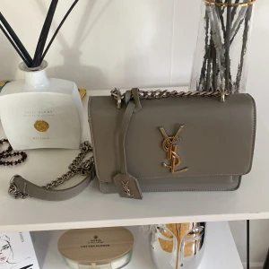 YSL damväska - Riktigt fin YSL väska som knappt är använd. Dock är vissa delar på kedjeremmen lite rostig, men inget som märks jätte tydligt.