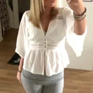 Vit blus med knappar från Zara XS - Supersöt vit blus från Zara i storlek XS. Blusen har v-ringning, trekvartsärmar och fina knappar framtill. Detaljer med spets och broderade band ger en romantisk vibe. Lätt och luftig i bomull, perfekt för vår och sommar.