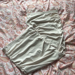 Beige långkjol med resårmidja - Säljer en enkel och stilren beige långkjol med resår i midjan. Kjolen har en rak passform och är tillverkad i ett mjukt, lätt material som känns skönt mot huden. Perfekt för dig som gillar minimalistisk stil.