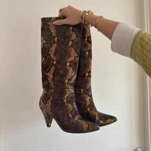 Ormboots - Säljer ett par höga boots i super coolt ormskinnsmönster. Skorna har spetsig tå och bekväm klack så perfekta för en utgång💃De är något slitna på klackarna vilket syns på bilderna🥰