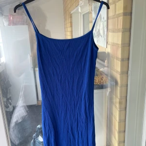 Blå ribbad klänning från Amisu - Säljer en blå ribbad klänning från Amisu med smala axelband och slits nertill.  Materialet är mjukt och stretchigt för en bekväm känsla.