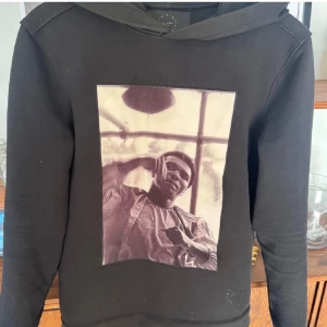 Svart hoodie Limitato x Muhammad Ali - Svart hoodie från Limitato med ikoniskt fototryck av Muhammad Ali på bröstet. Finns inte att köpa längre och säljs på grund av att den inte kommit till användning! finns inga defekter! hör av dig vid frågor och funderingar!