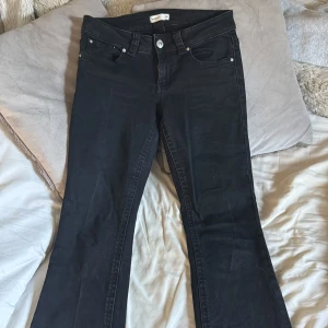Svarta bootcut jeans från Perfect Jeans Gina tricot  - Svarta jeans från Perfect Jeans Gina tricot med bootcut passform. Klassisk femficksmodell med silverfärgade knappar och detaljerade bakfickor med lock. Jeansen är lågmidjande och är tillverkade i ett stretchigt bomullsmaterial. Har använt dessa 1 gång 