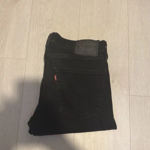 Svarta Levi's 511 jeans slim fit - Snygga svarta Levi's 511 jeans med slim fit, Klassisk femficksmodell med Levi's ikoniska röda etikett på bakfickan och svart läderpatch i midjan. Jeansen är i stretchigt denim som sitter tajt längs benen och har en modern look. OBS DOM SITTER KORTARE ÄN L32 