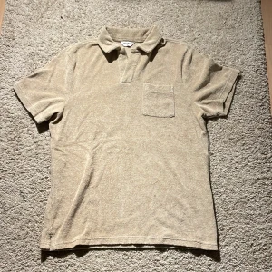 Beige frotté piké från East West - Beige t-shirt från East West i mjuk frotté med klassisk krage och bröstficka. Kortärmad modell med relaxed vibe, perfekt för chill dagar. Enkel och stilren design som passar till det mesta. Bara att fråga om du har några funderingar! Priset kan diskuteras vid snabb affär.