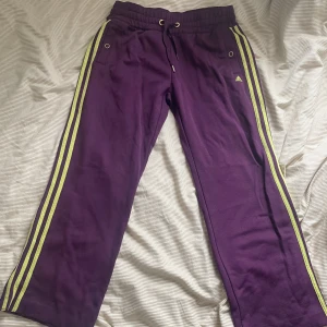 Lila Adidasbyxor med gula ränder - Säljer ett par lila mjukisbyxor från Adidas med klassiska gula ränder längs sidorna. Skitsnygga och knappt använda