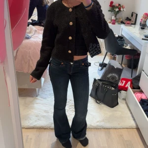 Svart kofta med guldknappar från Gina tricot  - Säljer en svart, fluffig kofta från Gina med rund halsringning och snygga guldknappar. perfekt att slänga på sig för en trendig look. Materialet är mjukt och känns lyxigt.