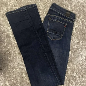 Mörkblå slimfit Replay jeans  - Snygga mörkblå jeans från Replay med klassiska kontrastsömmar och raka ben. Byxorna har fem fickor, Replay-logga på myntfickan och bakfickan, samt läderpatch i midjan. Perfekta för dig som gillar stilrena och tidlösa jeans.
