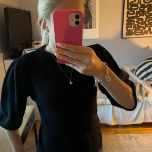 Svart stickad klänning med puffärm - Svart stickad klänning med trendiga puffärmar och rund halsringning. Mjuk och skön, perfekt för dig som gillar en stilren look med en twist. Passar lika bra med sneakers som boots. Är avklippt i ärmarna