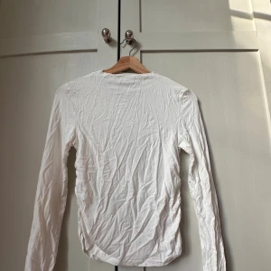 Vit långärmad topp från Stradivarius - säljer en vit långärmad topp från Stradivarius i mjuk bomull. Snygg rynkdetalj längs sidorna som ger en cool twist till en annars basic tröja. Perfekt att styla med jeans eller kjol för en clean look. Köpt i polen så kostade ca 500 kr men säljer för 300 kr Pris kan diskutera🩷