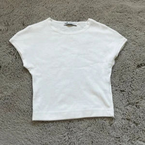 Vit croppad topp från Zara - En enkel och fräsch vit croppad topp från Zara med rund hals och korta ärmar. Är ganska liten i storleken💗