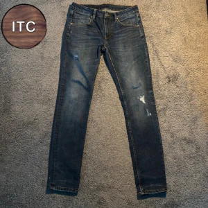 Mörkblå jeans med slitningar - Snygga mörkblå slimfit jeans med slitna detaljer på benen och klassisk femficksdesign. Jeansen har en slim passform och är tillverkade i ett stretchigt denimtyg.