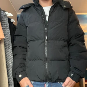 Svart pufferjacka med huva, Levis - Säljer en svart pufferjacka med huva och dragkedja framtill. I princip helt ny använd några gånger. 10/10 skick, rikitigt varm och snygg till vintern