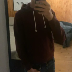 Vinröd hoodie från Pier One - Vinröd hoodie från Pier One med vita snören och huva. Klassisk modell med lång ärm och känguruficka framtill. Mjuk och skön, perfekt för kyliga dagar. Passar dig som gillar något enkelt men stilrent. Knappast andvänd då den var för liten.