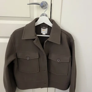 Brun kappa  - Snygg brun kappa från Gina Tricot Young. Använd endast en gång, ser alltså helt ny ut.