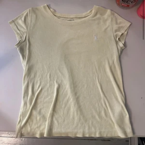 Gul t-shirt från Polo Ralph Lauren - Snygg gul t-shirt från Polo Ralph Lauren med klassisk broderad logga på bröstet. T-shirten har rund halsringning och korta ärmar. Tillverkad i mjuk bomull som känns skön mot huden. Perfekt för en avslappnad och stilren look. Något nopprig❣️