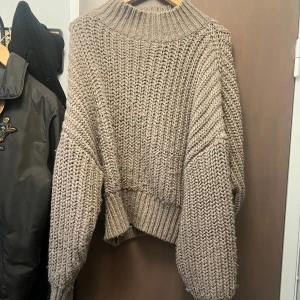 Beige chunky stickad tröja - Säljer en beige chunky stickad tröja med oversized passform och bred ribbad krage. Tröjan har långa ärmar och grovstickat mönster som ger en riktigt mysig vibe. Perfekt för kyliga dagar och enkel att styla till jeans eller kjol.