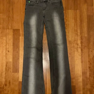 Grå bootcut jeans Cheap Monday 26/32 - Grå jeans från Cheap Monday i bootcut-modell med snyggt slitna detaljer längs benen. Klassisk femficksdesign och normal passform. Jeansen har en cool tvättad look och är tillverkade i bomull med lite stretch för extra komfort.