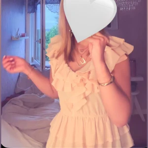 Ljus volangklänning med v-ringning - Supersöt ljus klänning med volanger och v-ringning, storlek S. Materialet känns lätt och luftigt.