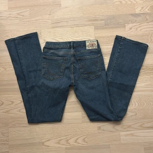 True Religion Becca Bootcut Jeans💙 - Snygga blå jeans från True Religion, modell Becca med bootcut och klassiska kontrastsömmar. Jeansen har medelhög midja och fem fickor, samt den ikoniska loggan på bakfickan. Tillverkade i slitstarkt denim med en cool vintagekänsla.
