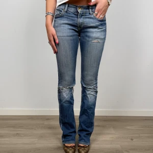 Blå bootcut jeans med slitningar - Snygga blå jeans med bootcut passform och slitna detaljer vid knän och bakfickor. Jeansen har klassisk femficksdesign, låg midja och är tillverkade i denim. ⚠️Jeansen har hål på rumpan vid fickorna, vilket gör dom unika!!