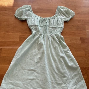 Mintgrön kort klänning  - Mintgrön klänning från Nelly. Klänningen har knytning vid bröstet. Den är från Bianca Ingrossos Nelly kollektion från sommaren 2022. 