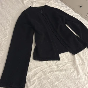Svart kofta från Gina Tricot  - En svart, klassisk kofta från Gina Tricot i storlek XS. Koftan har rund halsringning, lång ärm och stängs med en knapp upptill. Den är stickad och har ribbade kanter vid ärmslut och nederkant. Perfekt att slänga över en topp när det blir kyligt. Skriv om ni har frågor💕