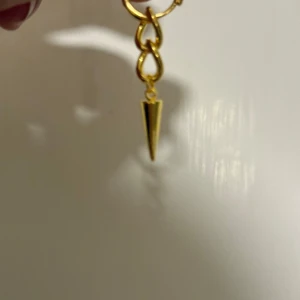 Guldiga örhängen med spike från Alvaz Essentials - Säljer ett par coola guldiga örhängen från Alvaz Essentials. Säljer helt oanvända pågrund av att ja råka beställa dubbelt  det är två stycken 